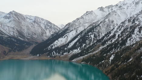 cinematic rotating drone footage of the turquoise colored lake water at big almaty lake in the trans-ili alatau mountains in kazakhstan