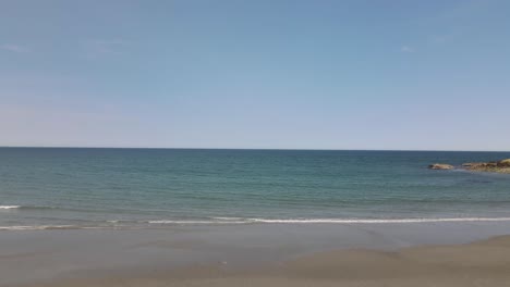 low aerial push forward over an empty nantasket beach, south of boston, with waves crashing in