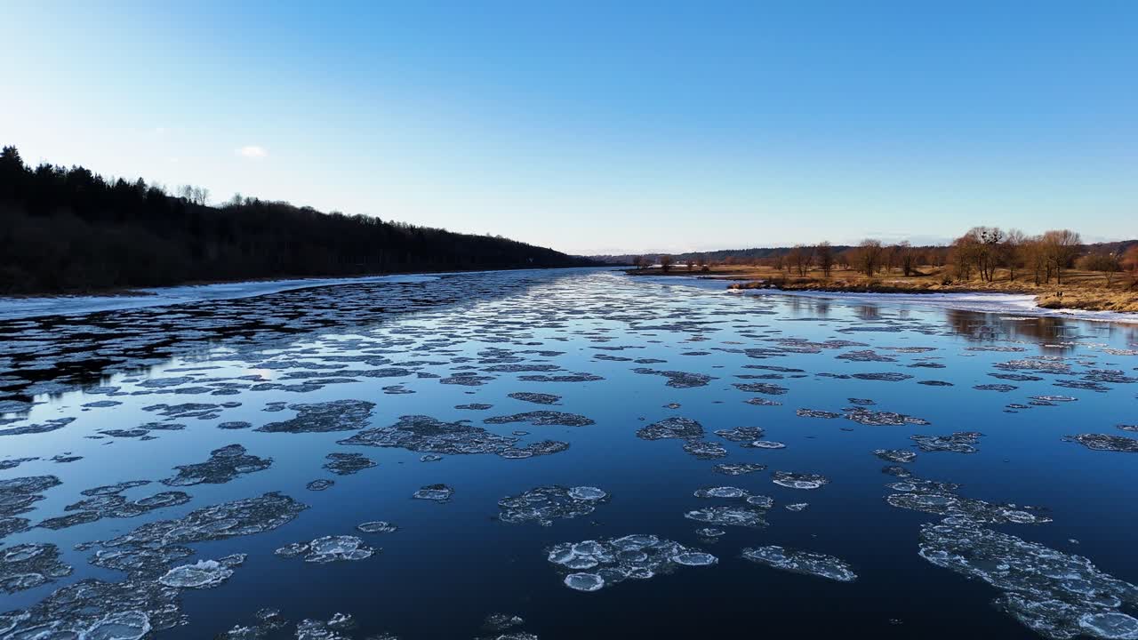 Ice on blue river water, low angle aerial view