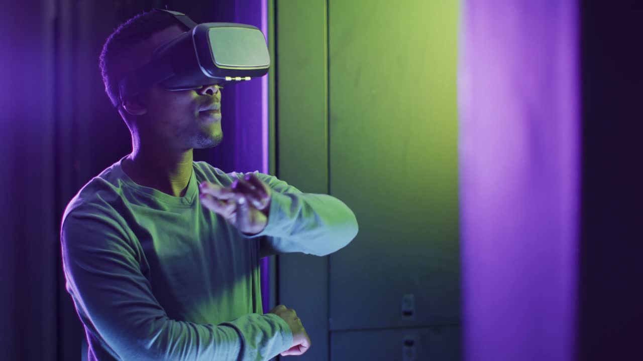 tecnico informatico maschio afroamericano che usa le cuffie vr che lavora in una sala server aziendale