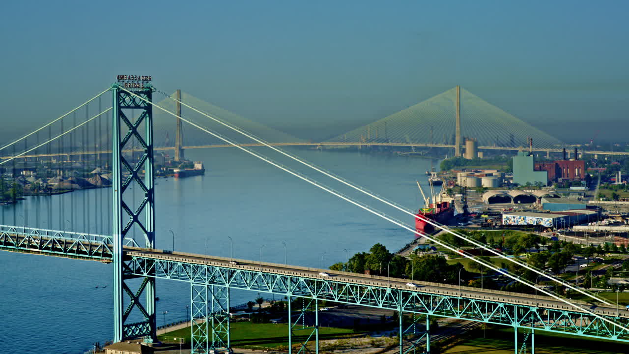 Cinematic bird’s-eye drone view flying over Detroit River with freighter and skyline below