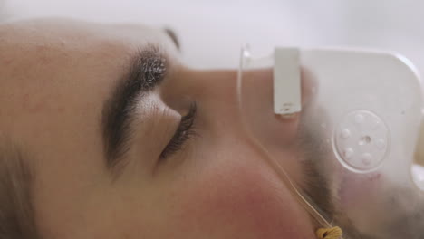 close up of a sick man lying on bed breathing through oxygen mask 1