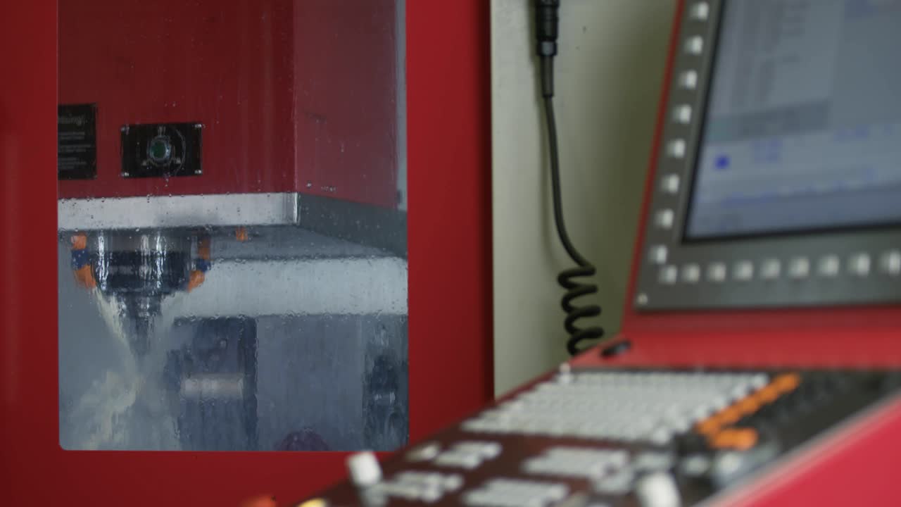 Outside view of a milling machine processing raw metal parts using coolants with a control unit in front