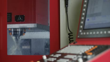 outside view of a milling machine processing raw metal parts using coolants with a control unit in front