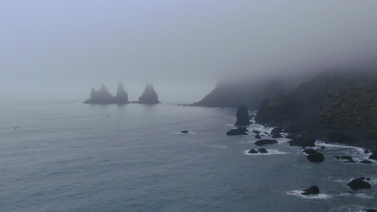 에어리얼 시네마틱 판 오른쪽 파도가  ⁇ 더미 해안선을 부 ⁇ 히고 비크 아이슬란드에서 날아다니는 새 검은 모래 해변 파도의 초기 겨울 안개