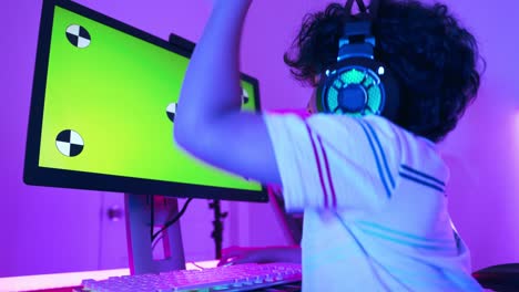 excited gamer  boy in headset with a mic playing online strategy video game on her personal computer.