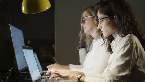 Mujeres-Empresarias-Que-Usan-Computadoras-Portátiles-En-Una-Oficina-Oscura