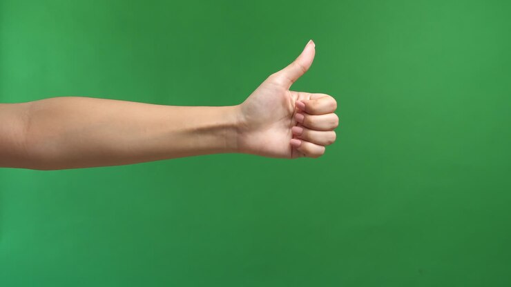 Closeup Of Female Hand Showing Thumbs Up Sign Against Green Screen Background