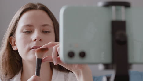 close up of beautiful vlogger girl reviewing a makeup brush for the camera