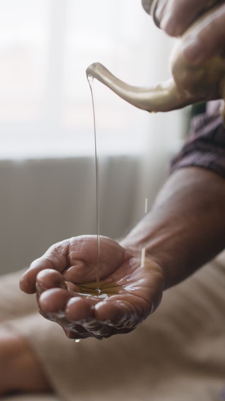 Ayurvedic oil pouring into hand for massage therapy