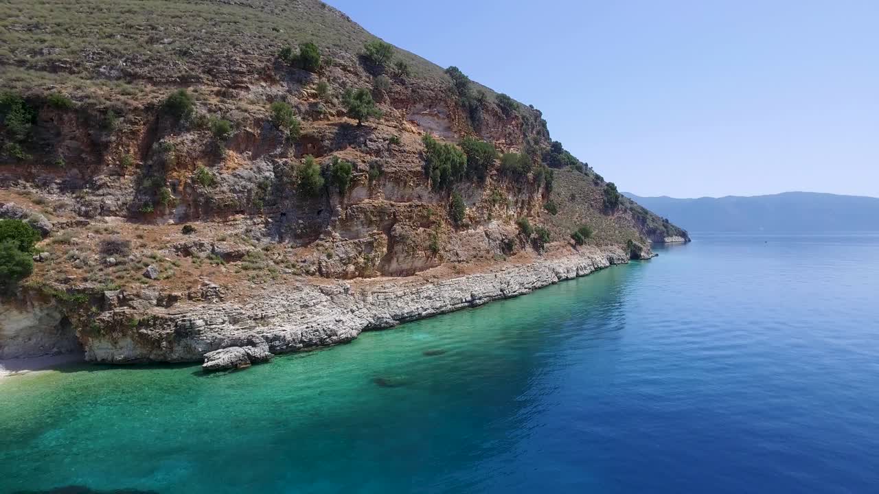 Retreating zipline drone shot along the rocky coastline of a secret beach in Agriosiko, located in Cephalonia off the coast of Greece