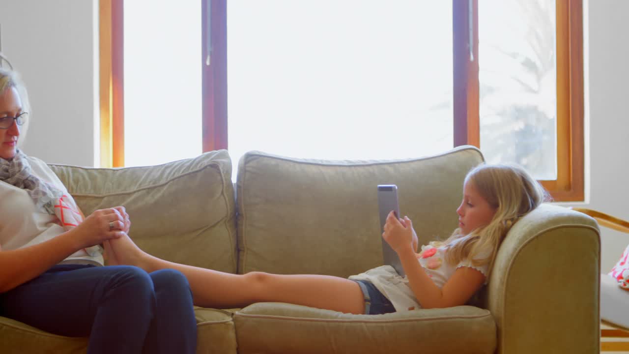 madre dando un masaje de piernas a su hija en la sala de estar 4k