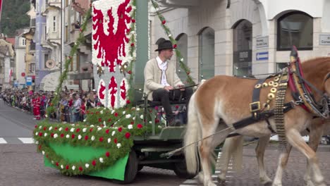 horse-drawn carriage with the city coat of arms made of flowers at the grape festival of meran - merano, south tyrol, italy