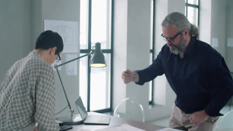 arquitecto masculino sénior estrechando la mano y hablando con una colega