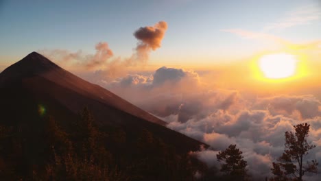 volcán activo con penacho de ceniza al atardecer vista increíble por encima de las nubes