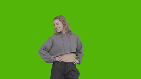 studio portrait of smiling young woman against green screen