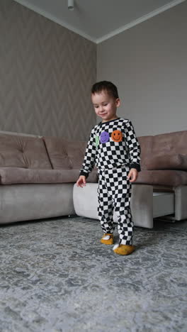 joyful toddler in checkered pajama plays at home. cheerful baby picks the toys and puts them into the drawer. vertical video.