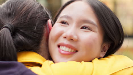 close up of two smiling young female friends meeting and hugging in urban setting together 1