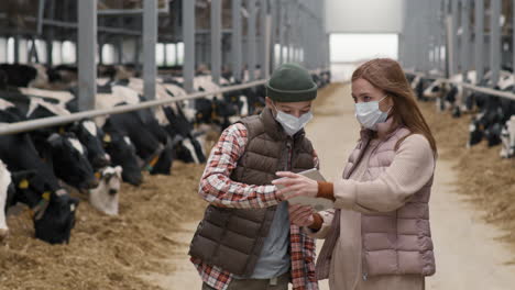 boy and woman in face masks using tablet at dairy farm