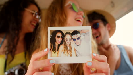 a cheerful young woman holding a polaroid