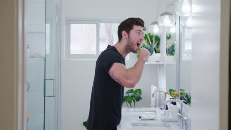 man wearing pyjamas standing at sink brushing teeth in bathroom