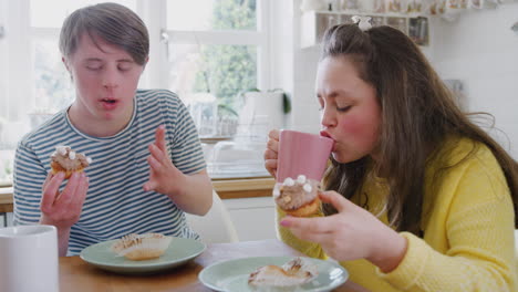 young downs syndrome couple enjoying tea and cake in kitchen at home