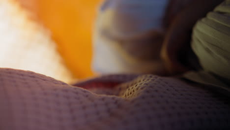 Child-girl-embraces-pillow-sitting-on-pink-cover-in-bedroom