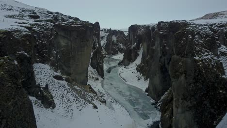 un desfiladero de islandia con hielo y nieve cubriendo el paisaje con un avión no tripulado volando hacia atrás