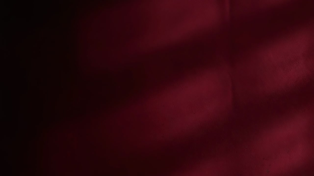 Tenda rosso scuro che si sposta mostrando fasce di luce lamellare vicino alla finestra, con luce in movimento attraverso le persiane
