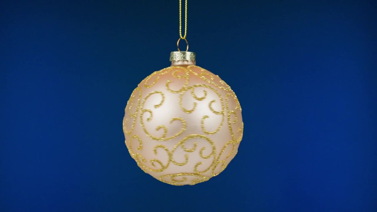 Rosa-goldener Glitzer-Weihnachtsschmuck hängt auf blauem Hintergrund