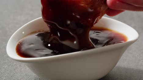 dipping a crispy chicken wing in sauce