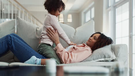 eine mutter und tochter lachen und spielen zusammen auf der couch
