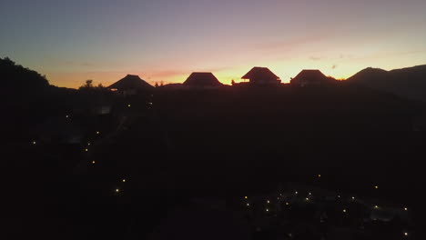aerial rises toward hilltop villa silhouette against late