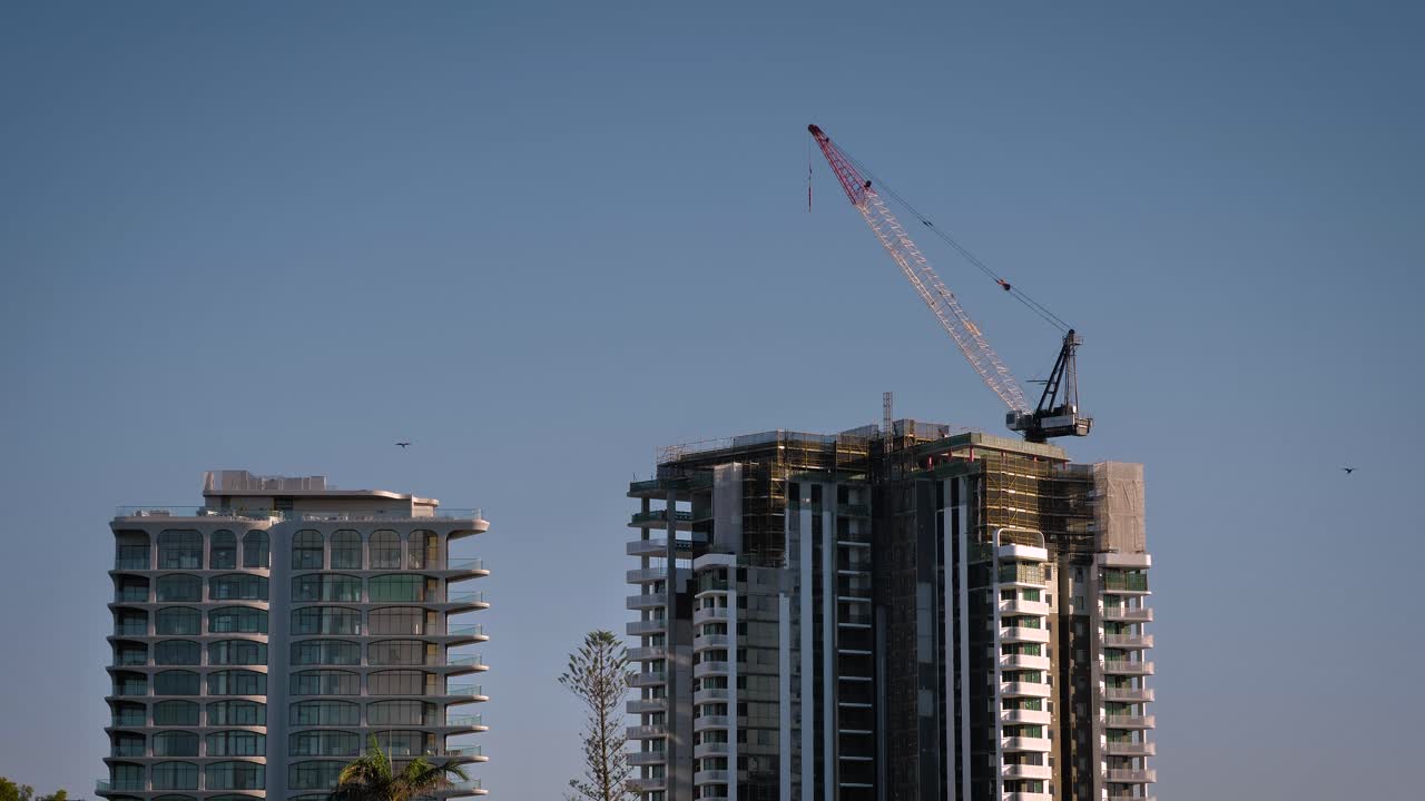 Tight shot of a construction crane on a Gold Coast high-rise apartment building in the morning on a sunny day, Queensland, Australia