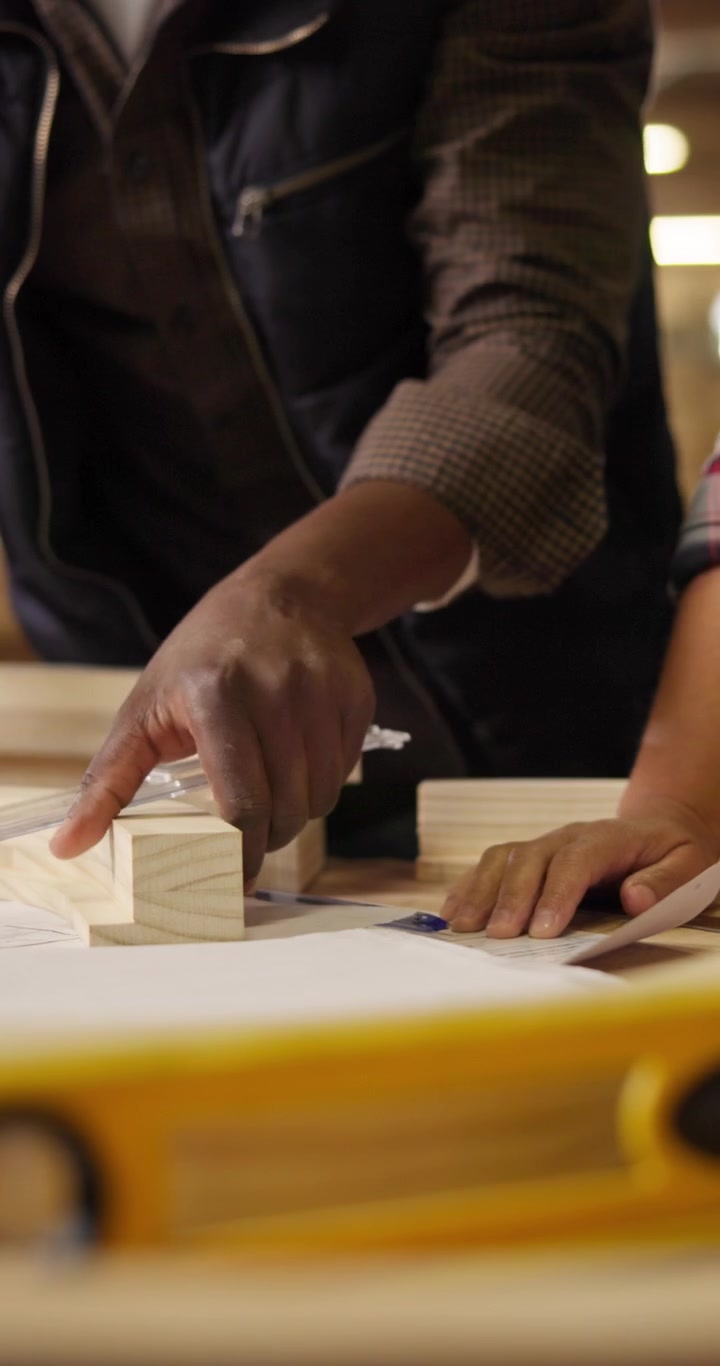 Falegnami esaminano progetti e pezzi di legno in officina