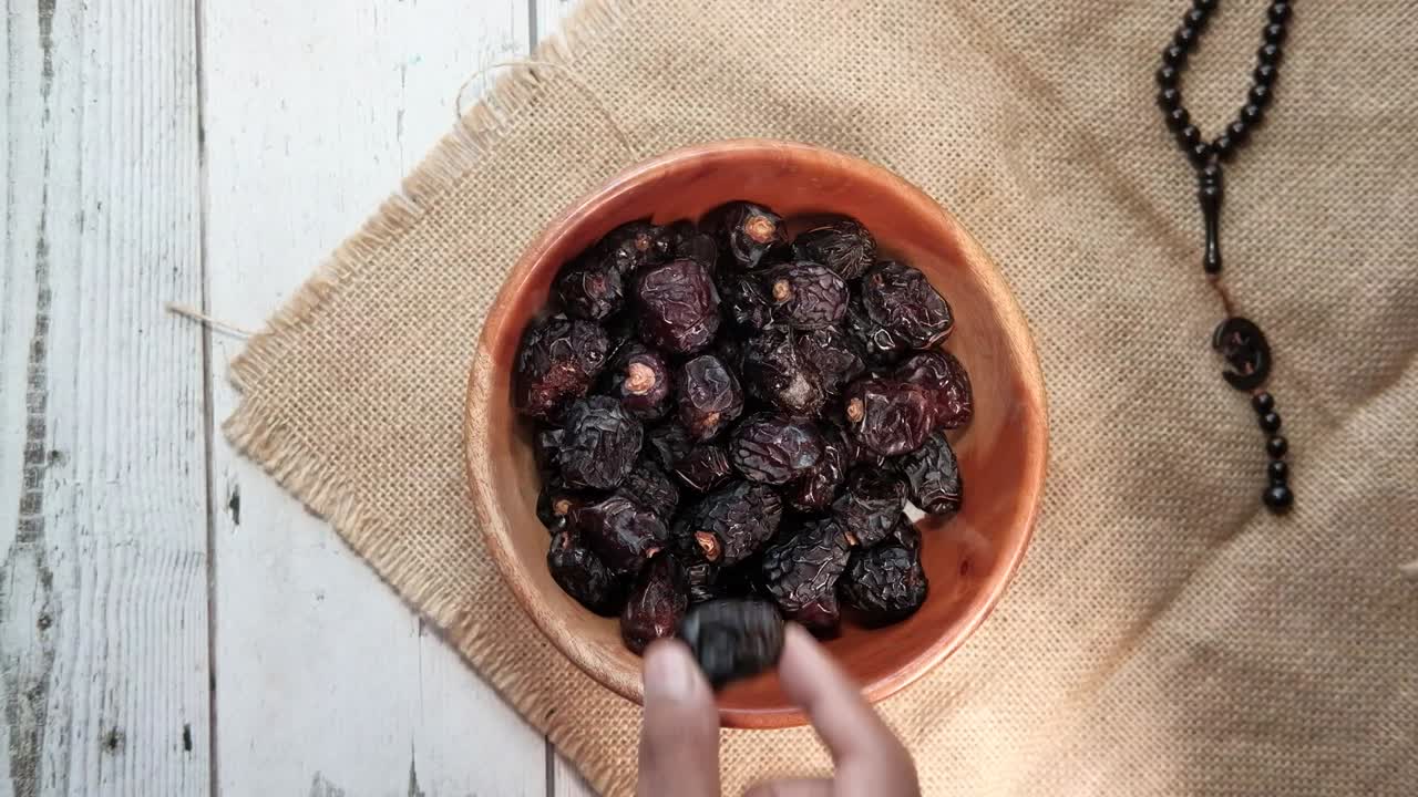 top view of man hand picking date fruit from a bowl