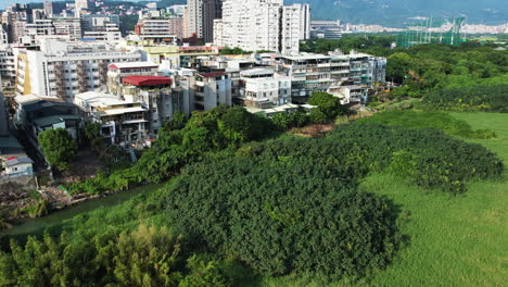 River-divides-Beitou-district-from-Guandu-wetlands-in-Taipei-Taiwan,-aerial-overview