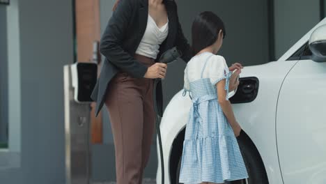 progressive lifestyle of mother and daughter with ev car and charging station.