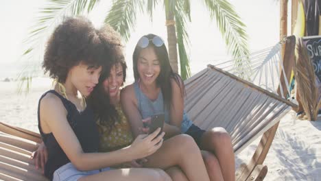mixed race friends watching phone in the hammock at beach
