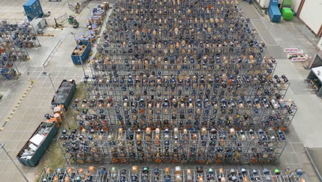 overhead aerial drone view of a meticulously arranged grid of metal racks storing cable reels, wiring components, and other electrical materials at an industrial site