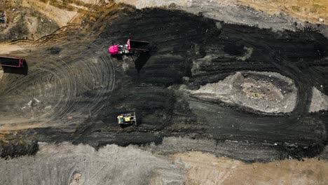 overhead drone shot looking down on a construction site where bulldozers and dump trucks are moving dirt on a bright, sunny day