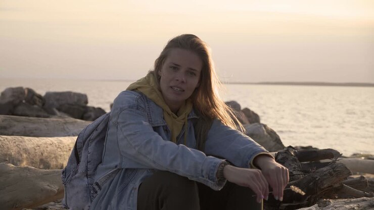 Unhappy girl sitting on the beach look at sunset