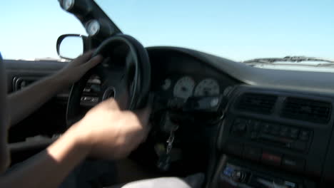 una toma de pov desde el interior de un automóvil mientras un piloto de pruebas en la pista lo lleva a través de maniobras durante la deriva