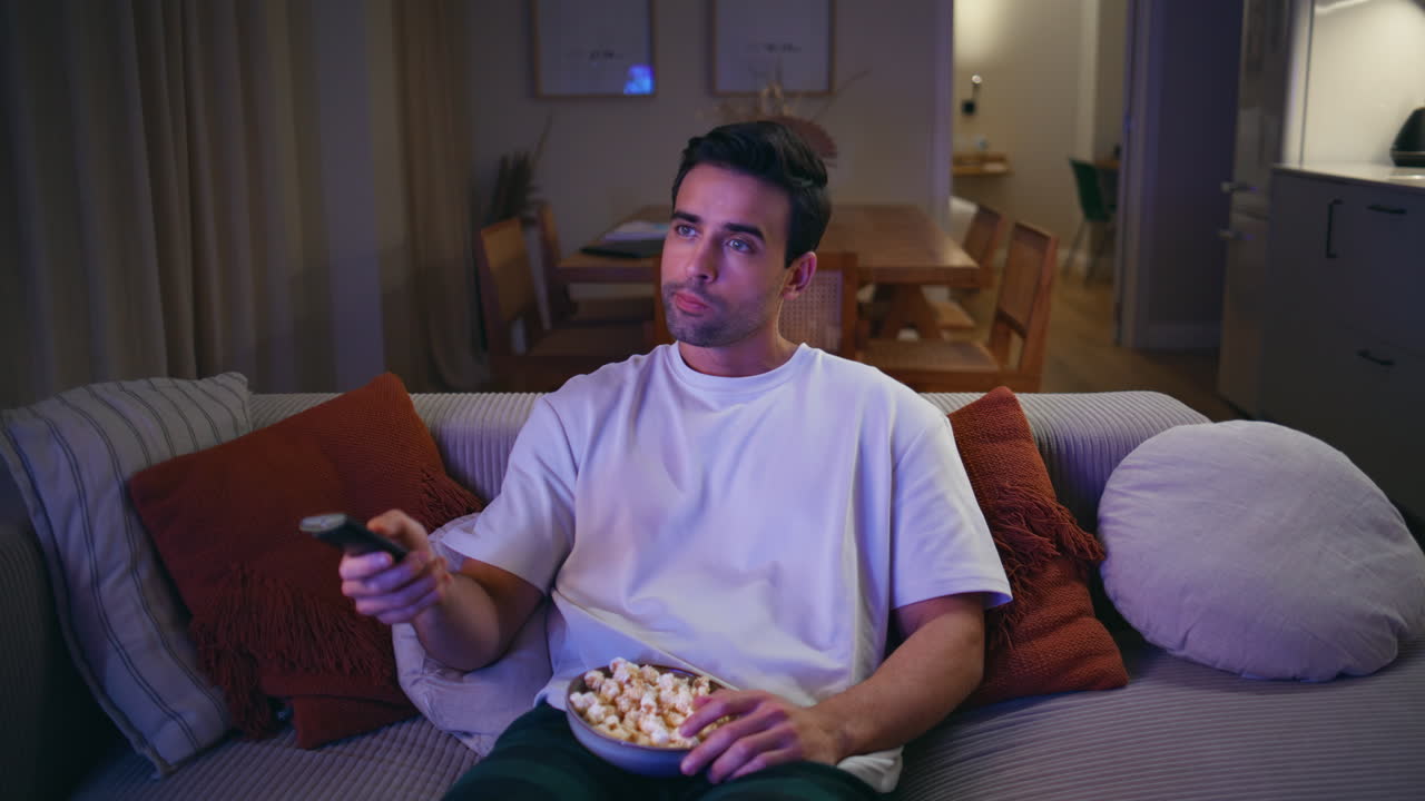 Relaxed guy watching movie on TV sitting cozy couch. Calm man enjoy television