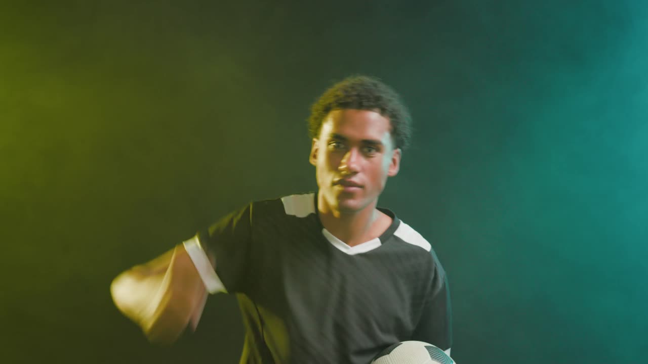 Uomo afroamericano che urla e poi agita il braccio destro per rivolgersi alla telecamera in studio con un pallone da calcio