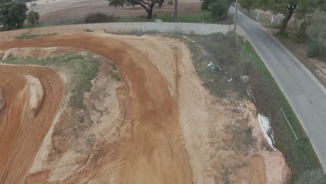 fpv aéreo en cámara lenta sigue la pista de tierra de motocross, el ciclista gira a su vez