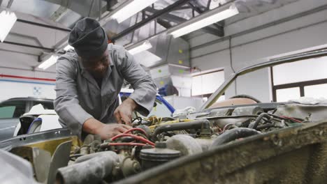 african american male car mechanic screwing screws in a car engine