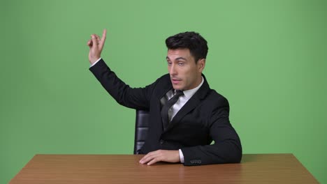 초록색 배경에 젊은 잘생긴 히스패닉 사업가