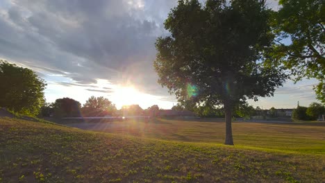 Blick-Auf-Grünflächen-Im-Stadtpark-Mit-Bäumen-Und-Hügeligem-Gelände-Bei-Sonnenuntergang-Im-Sommer