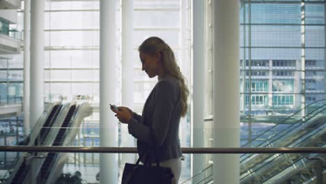 Businesswoman-talking-on-mobile-phone-in-the-lobby-at-office-4k